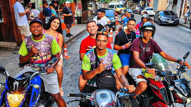 Grupo de turistas e condutores com as motos numa rua da comunidade